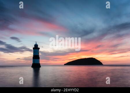 Sunrise at Penmon Point, Anglesey, Wales, United Kingdom. Penmon (Trwyn Du) lighthouse and Puffin Island.  Dramatic, colourful skiy and smooth sea. Stock Photo