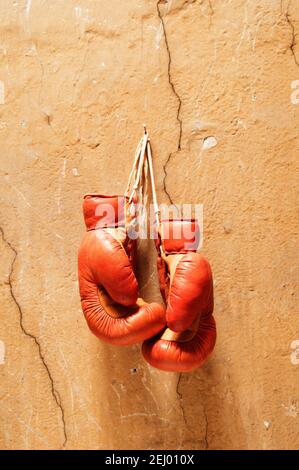 Old boxing gloves hanging on a cracked wall, showcasing a sense of nostalgia and the spirit of the sport Stock Photo