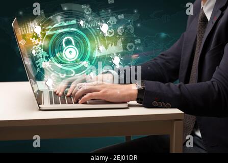 Business hand typing on a modern laptop with lock icon coming out from multimedia screen, intuitive technology concept Stock Photo