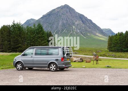 Camper Van parked next to deer and Buachaille Etive Mor mountain in the KingsHouse Hotel car park, Glencoe, Scottish Highlands, Scotland, UK Stock Photo