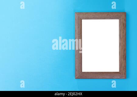 empty wooden picture frame with white interior on light blue wall Stock Photo