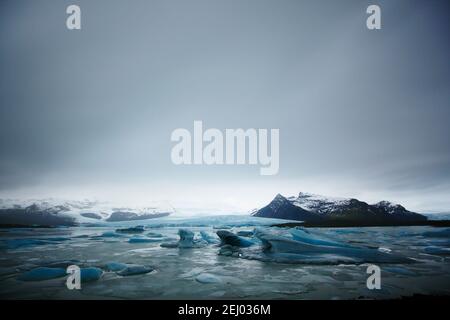 Many glaciers float and drift on the calm Fjallsarlon Glacier Lake in Iceland. Stock Photo