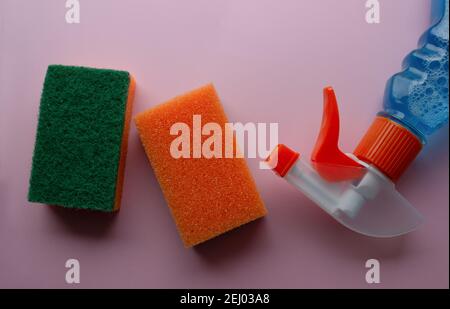 two orange a sponge for cleaning and blue cleaning liquid Close-up on pink background. Stock Photo
