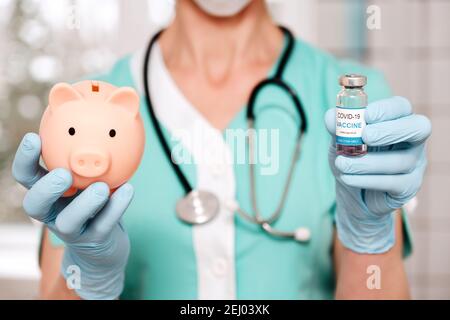 Doctor hands holds vaccine vial and piggy bank Stock Photo