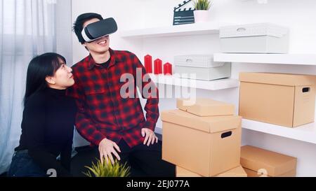 Young couple moving in. Young man using VR glasses. High quality photo Stock Photo