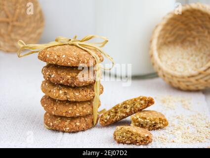 Stack of Sesame cookies, sesame seeds in a wicker basket, rough woven tablecloth, copy space, day light Stock Photo