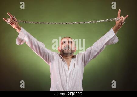 A bearded short-haired elderly man with a chain in his hands shows a rockers goat Stock Photo