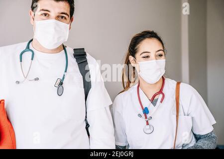 Male and female doctors wearing protective medical masks and phonendoscopes standing in clinic Stock Photo