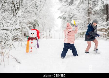 Cute boy and girl building snowman in winter forest Stock Photo