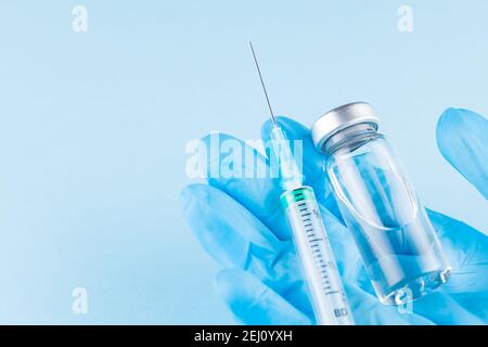 Vaccine vial and syringe in doctor hand. Doctor's hand in surgical glove holding a vaccine vial and syringe. Vaccination and immunization Stock Photo