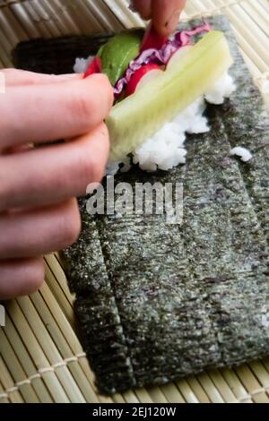 Woman using bamboo rolling mat for home made sushi Stock Photo - Alamy