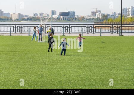 Kazan, Russia-September 26, 2020: Children play and roll on the artificial lawn of the artificial football field in the city park on the embankment on Stock Photo