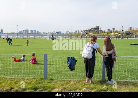 Kazan, Russia-September 26, 2020: Residents of the city relax and play with children on the lawn of an artificial football field in the city park on t Stock Photo