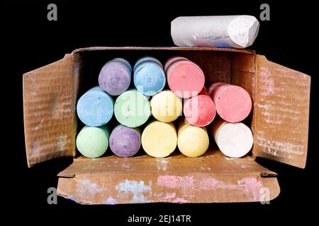 A box of colored chalk for street drawing. School chalk in a cardboard box. Dark background. Stock Photo