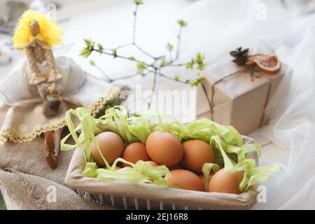 Spring composition. A toy doll, eggs in a basket and a festive box with a gift Stock Photo