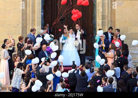 Newly weds celebrating the occasion with family and friends whilst leaving the St. George's Basilica in Victoria (Gozo), Malta Stock Photo