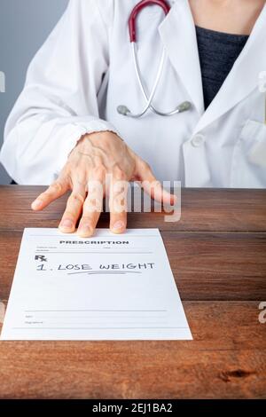 A caucasian female physician in white coat is prescribing Lose weight to an obese or overweight patient in her office. A concept image for lifestyle m Stock Photo