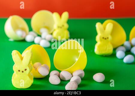 Easter egg hunt concept made with crisp sugar shell coated chocolate eggs and marshmallow easter bunnies. Three little bunnies  with small sweet eggs Stock Photo