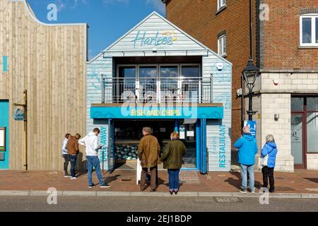 Poole, Dorset, UK - October 14 2020: People queue outside Harlees fish and chip shop on Poole Quay Stock Photo
