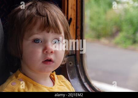 Baby girl sitting by a train window
