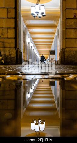 Wroclaw February 10 2020 Long arcades tunnel with walking people at night reflected in puddle Stock Photo