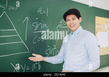 young smiling teacher standing in front of chalkboard Stock Photo