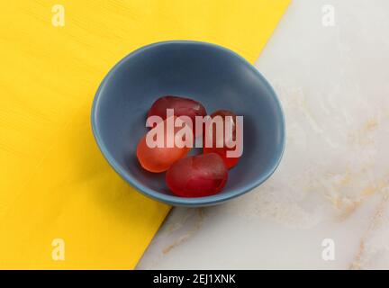 Cranberry and pink grapefruit juice filled Jelly gummy candy pieces in blue bowl on yellow napkin on table Stock Photo