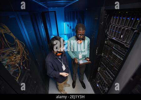 High angle view at two young technicians setting up server network while working in data center, copy space Stock Photo
