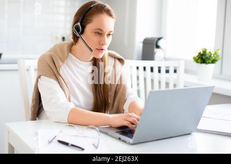Photo of a woman during an online conversation. She sits on the couch at home and having conversation via video communication. Stock Photo