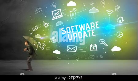 Businessman defending with umbrella from SOFTWARE UPDATE inscription, modern technology concept Stock Photo