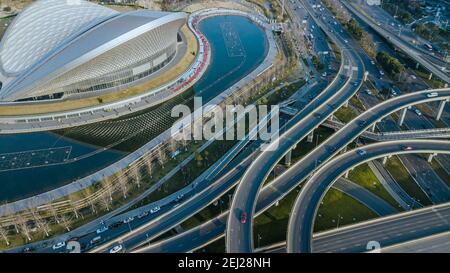 Breathtaking aerial high angle view of developed Chinese city. Multi-level elevated traffic junction, building of open air music park concert hall Stock Photo