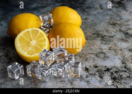 Four lemons and ice cubes on a gray background. Lemon sliced. Fresh fruit. Stock Photo