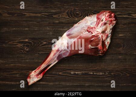 Overhead view of raw deer leg over wooden background Stock Photo