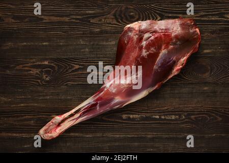 Overhead view of raw deer leg over wooden background Stock Photo