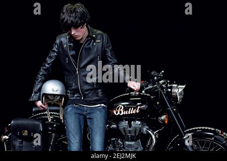 Young biker in  black leather jacket with classic style motorcycle and black backround.Male biker indoor with cafe racer. Stock Photo