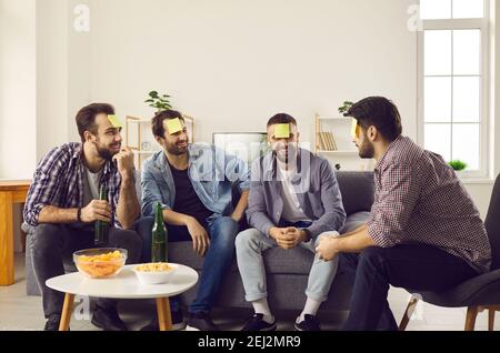 Male friends gathered at home on the weekend and had fun playing the game Who am I. Stock Photo