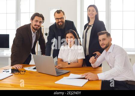 Group portrait of happy smiling business people near laptop in business center office. Stock Photo
