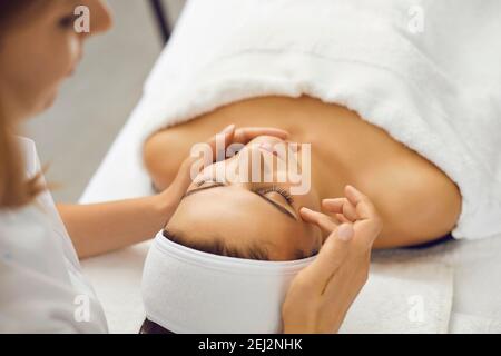 Cosmetologist or dermatologist putting cream on face for woman during beauty treatment Stock Photo