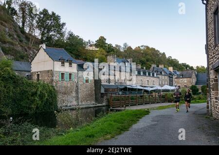 Man and woman running along the Canal de la Rance as they pass through the city of Dinan. France October 2018. Stock Photo