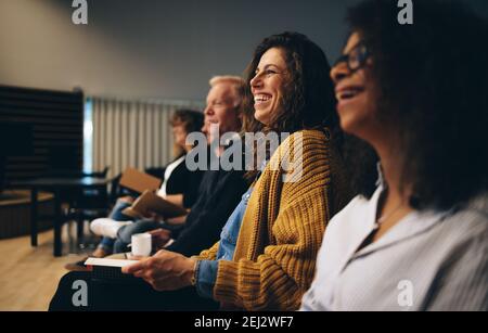 Audience listening to the speech of the speaker and smiling. Group of business people attending a convention. Stock Photo