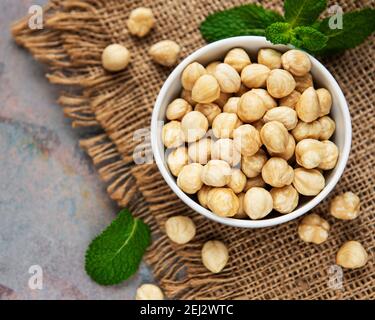 Peeled hazelnuts in a bowl on grey concrete background Stock Photo