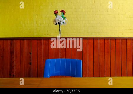Blue chair and bright yellow wall with a small bouquet of flowers with plenty of copy space. Stock Photo