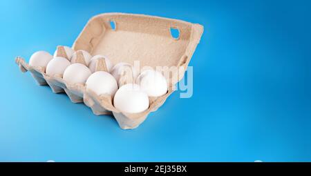 Farm raw, fresh white chicken egg in an egg box on a blue background. Eggs in carton. Eggs in the basket. Concept: a fresh egg for the morning breakfa Stock Photo