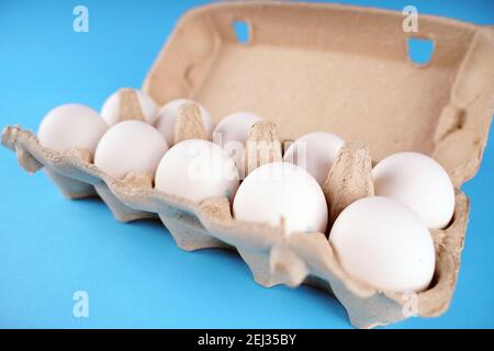 Farm raw, fresh white chicken egg in an egg box on a blue background. Eggs in carton. Eggs in the basket. Concept: a fresh egg for the morning breakfa Stock Photo