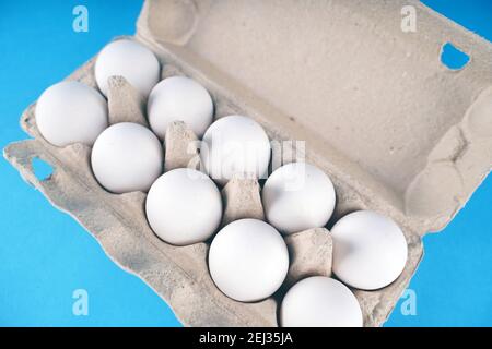 Farm raw, fresh white chicken egg in an egg box on a blue background. Eggs in carton. Eggs in the basket. Concept: a fresh egg for the morning breakfa Stock Photo