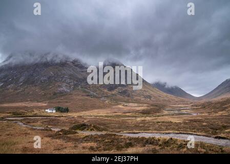Stunning landscape image view down Glencoe Valley in Scottish Highlands with mountain ranges in dramatic Winter lighting Stock Photo