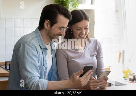Overjoyed millennial couple have fun using cellphones Stock Photo