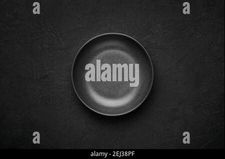 An empty black bowl on dark slate table top. Rough ceramic bowl background with copy space Stock Photo