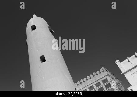 Monochrome, black and white image of the minaret of the Siyadi Mosque, the Siyadi House (Beit Siyadi) behind, on the Pearl Trail, Muharraq, Bahrain Stock Photo