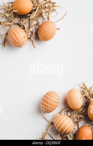 Frame of Easter eggs and straw on white background. Flat lay, top view, copy space. Easter vertical banner mockup. Stock Photo